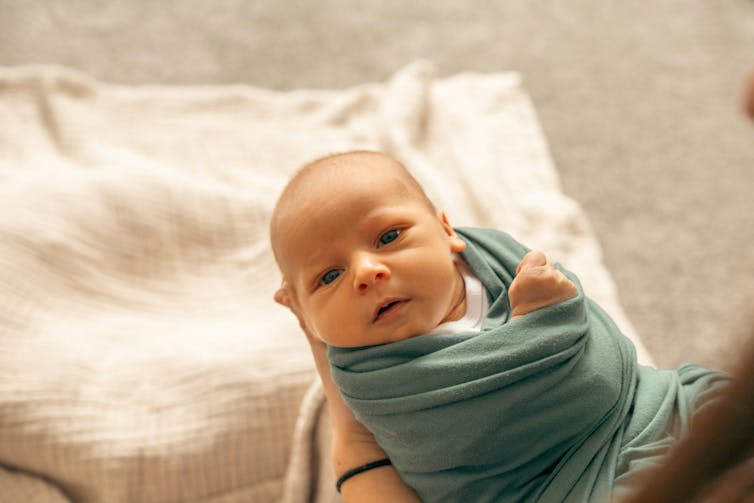 An infant wrapped in a green blanket