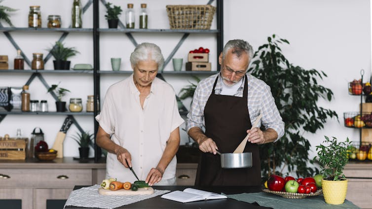 A man and a woman with grey hair preparing food