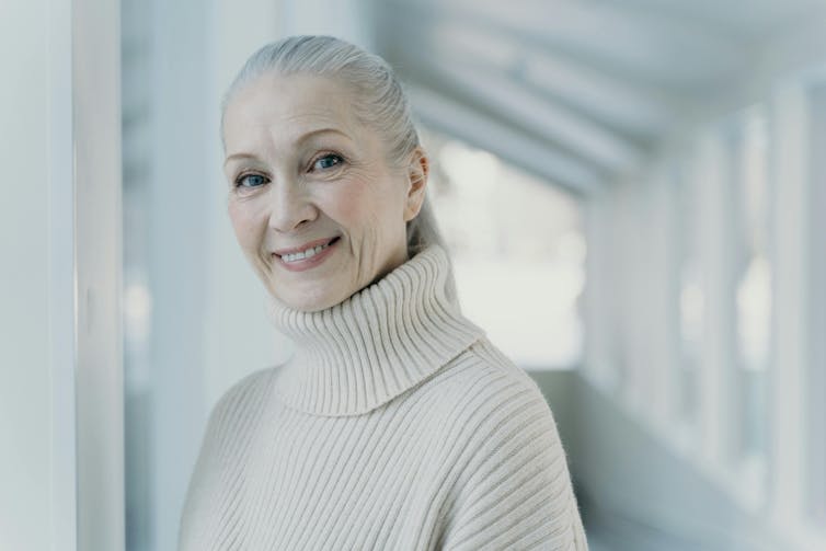 A woman with her grey hair pulled back smiling