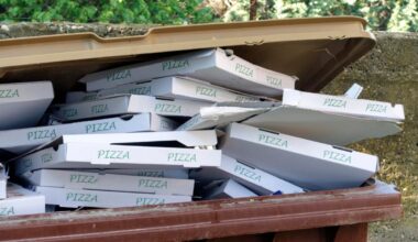 pizza boxes piled in a garbage can