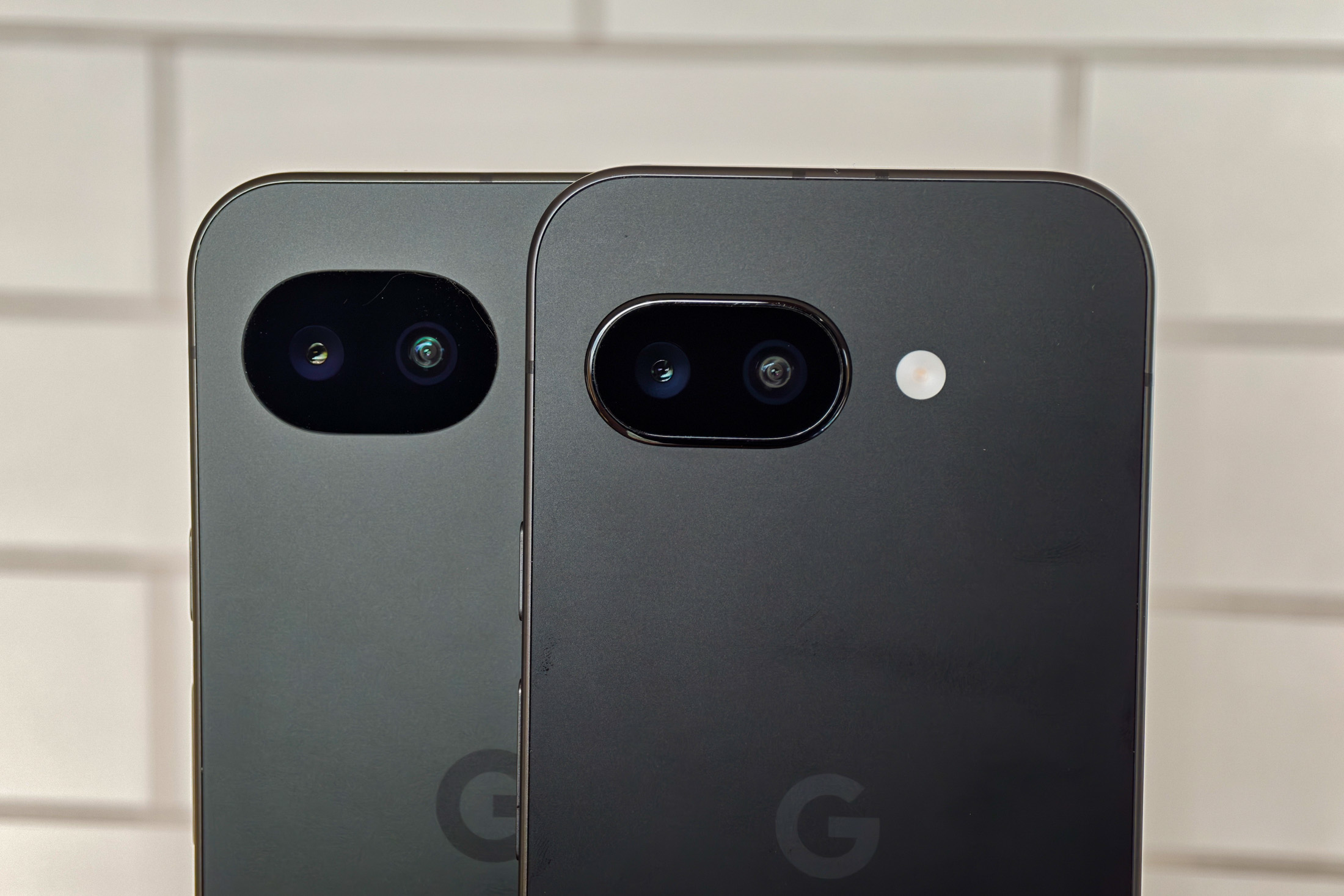 Photo of Google Pixel 10A and 9A side by side in front of white tiles