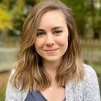 Brown haired white woman wearing a light blue sweater looks directly into camera