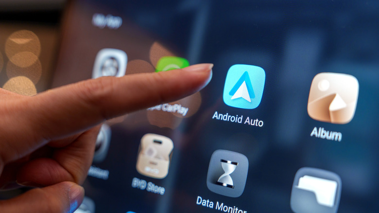 A finger pressing the Android Auto icon on a vehicle display