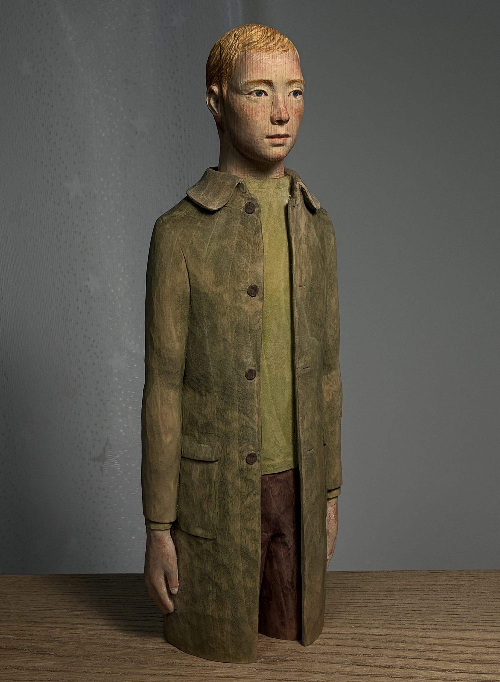 A figurative, painted wood sculpture of a young man in three-quarter profile by Shinsuke Inoue