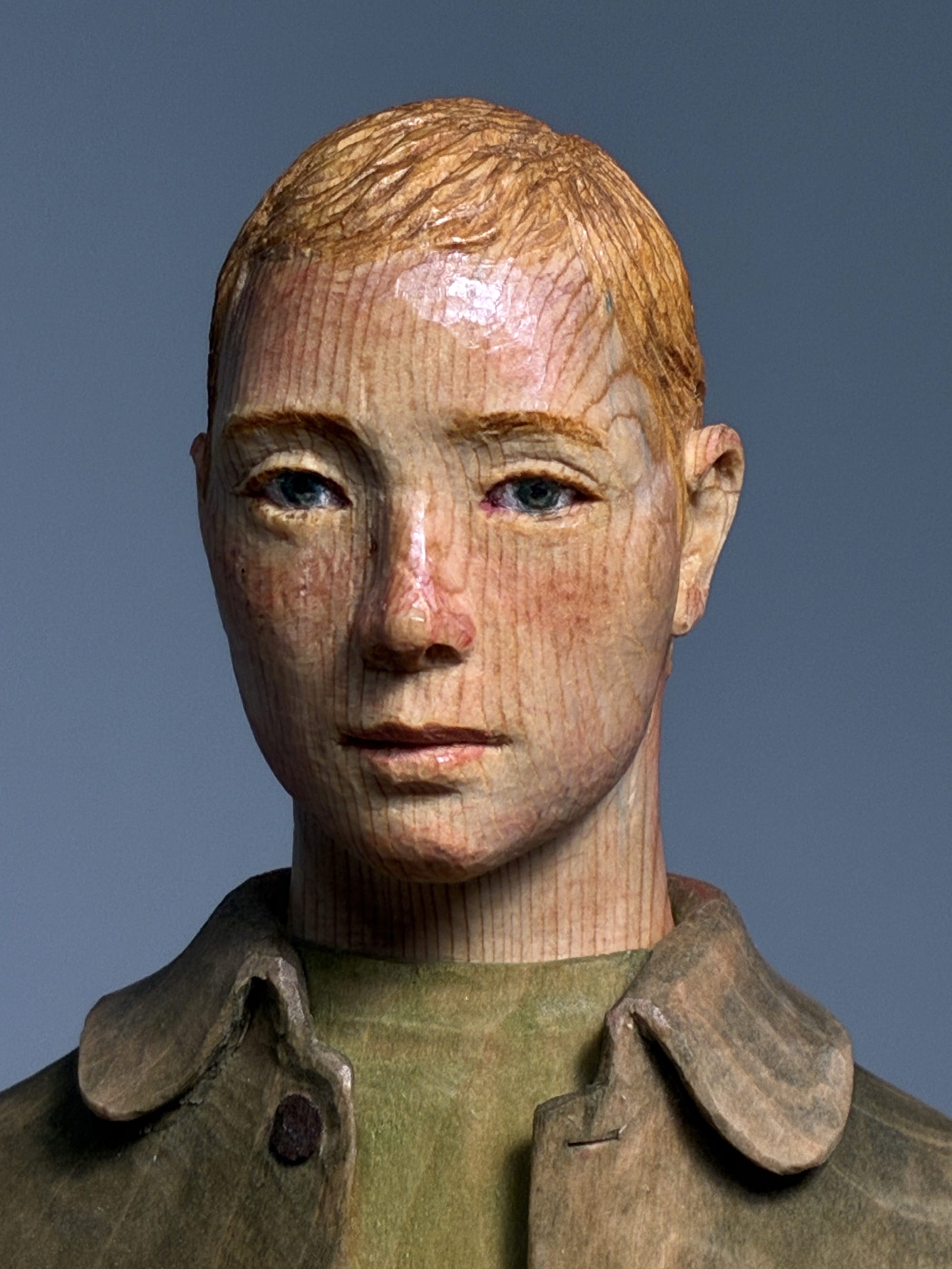 A detail of a figurative, painted wood sculpture of a young man by Shinsuke Inoue