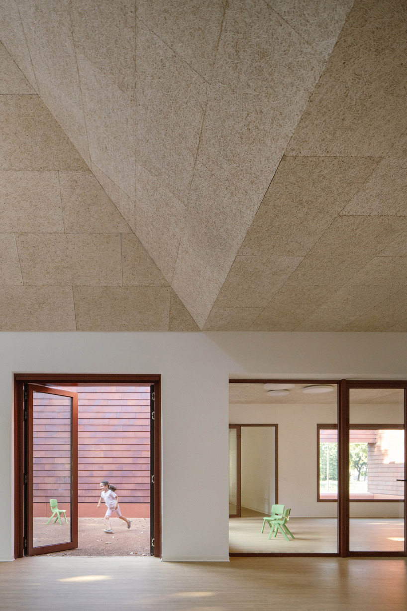 a cluster of terracotta-tiled pyramidal houses envelopes kindergarten in italy - 12