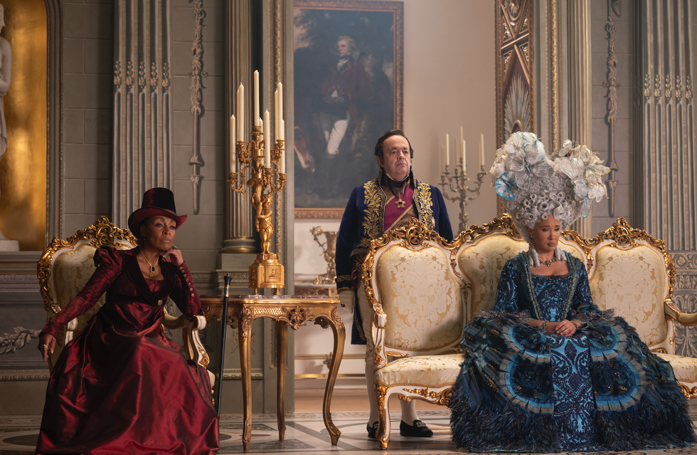 three elegantly dressed individuals in a lavish indoor setting