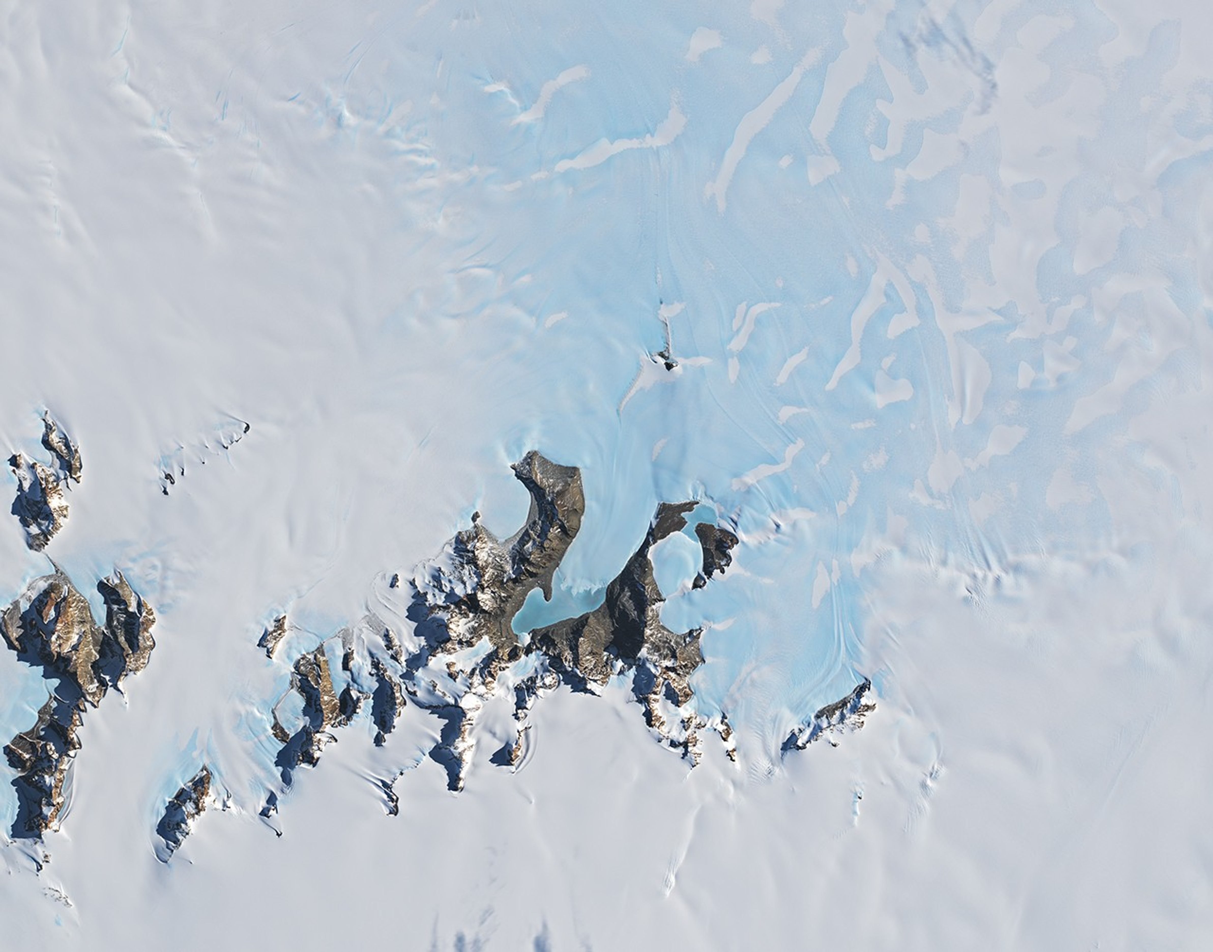 The image is centered on Anuchin and Ober-See glaciers in Antarctica. They appear as bright white patches separated by brown rocky ridges. Both glaciers have ice-covered meltwater lakes draining from their termini. Lake Unter-See is the larger of the two lakes.