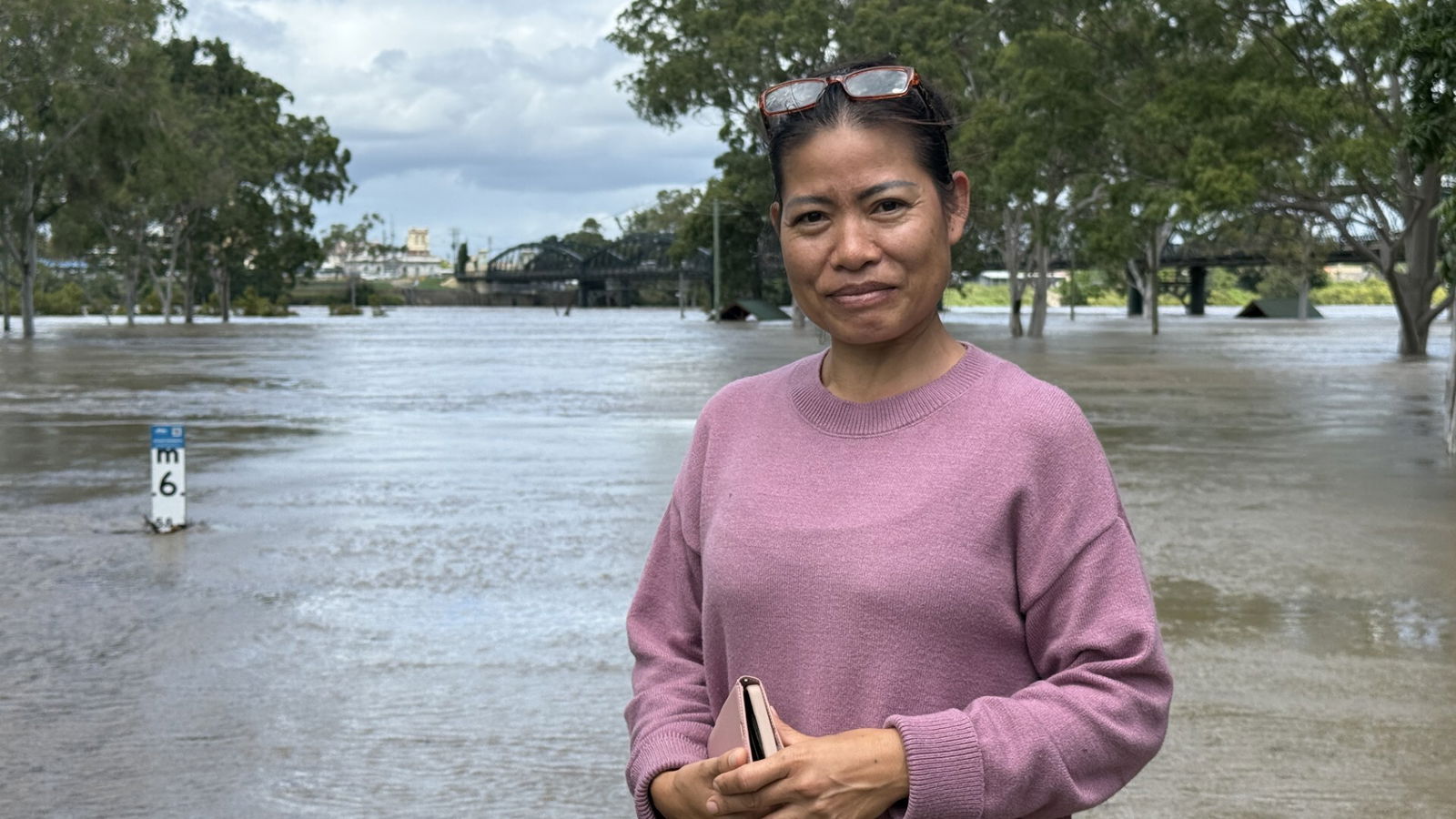 A woman in a pink jumper near a flooded river