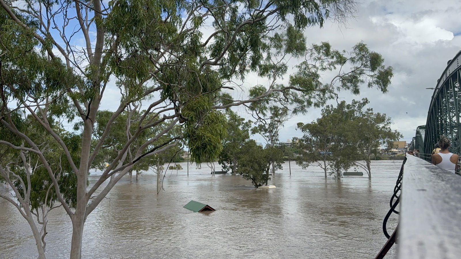 Water rises over building structures near a river. 
