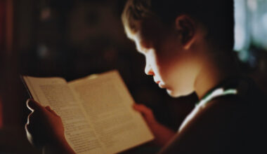 Young boy reading book under low light