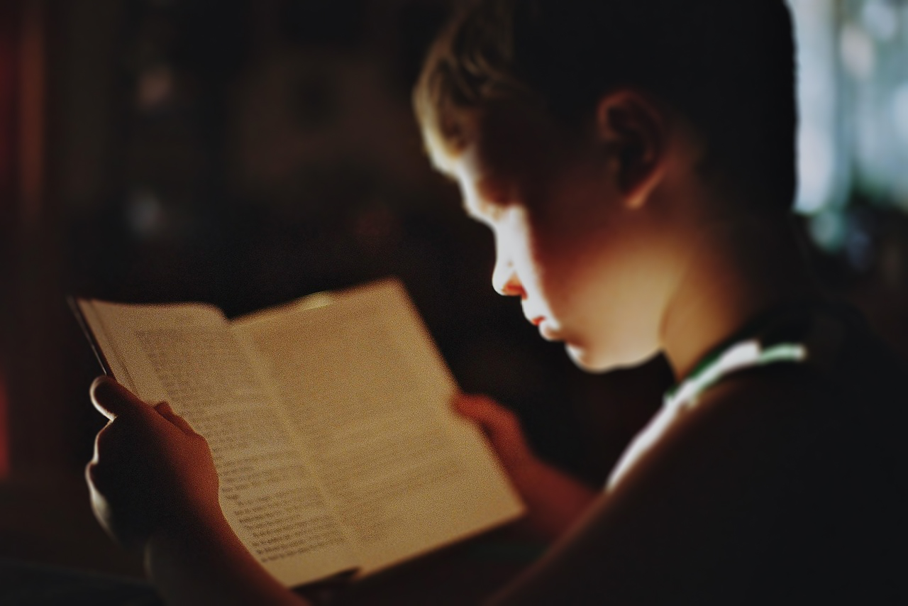 Young boy reading book under low light