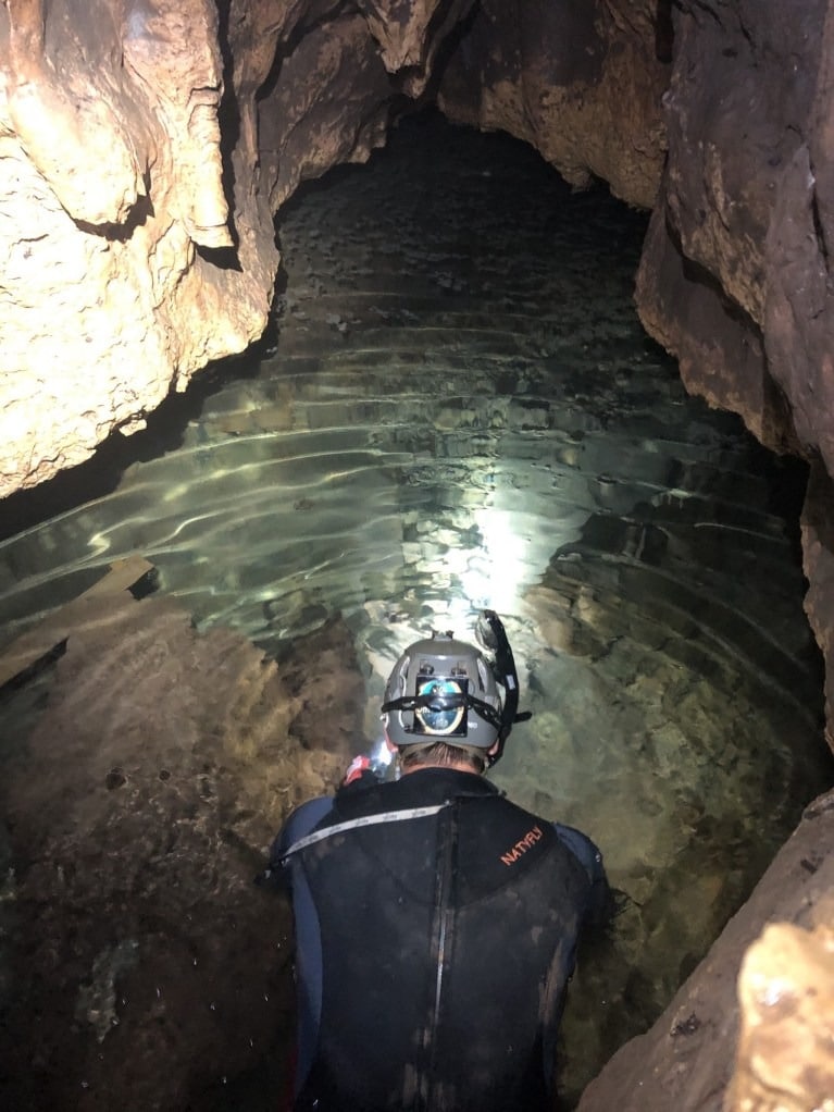 Paleontologist John Moretti Searched For Fossils In The Stream Flowing Through Bender’s Cave, Wearing A Wetsuit And Goggles.