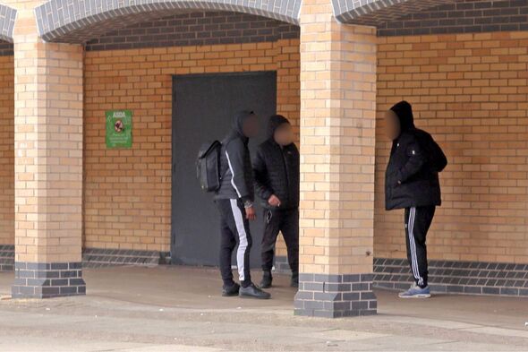 three men dressed in black outside asda in peterborough