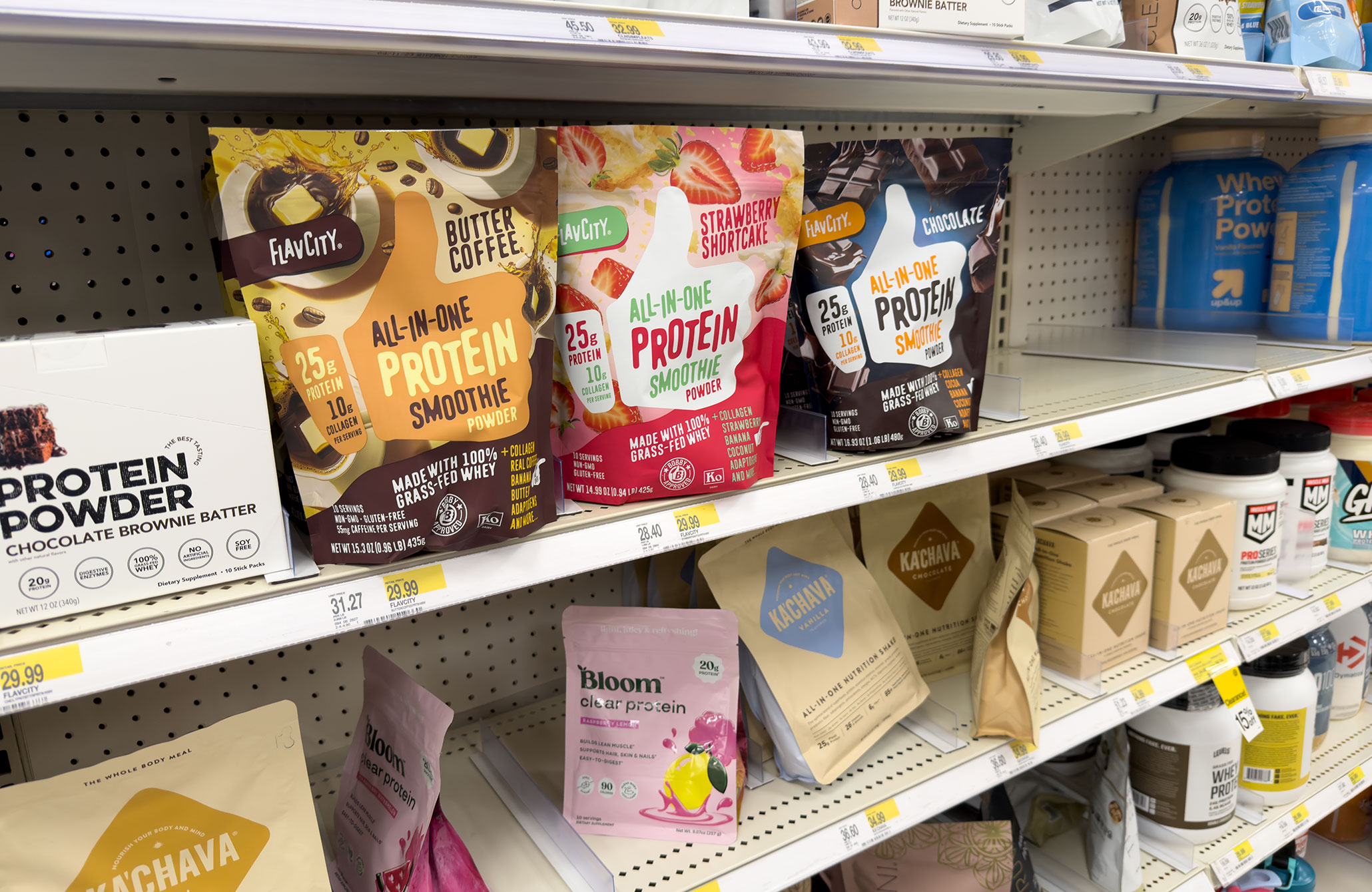 Photo of a protein aisle at Target showing an All-in-one protein smoothie in a butter coffee flavor, as well as strawberry shortcake and chocolate, among several other protein powders.