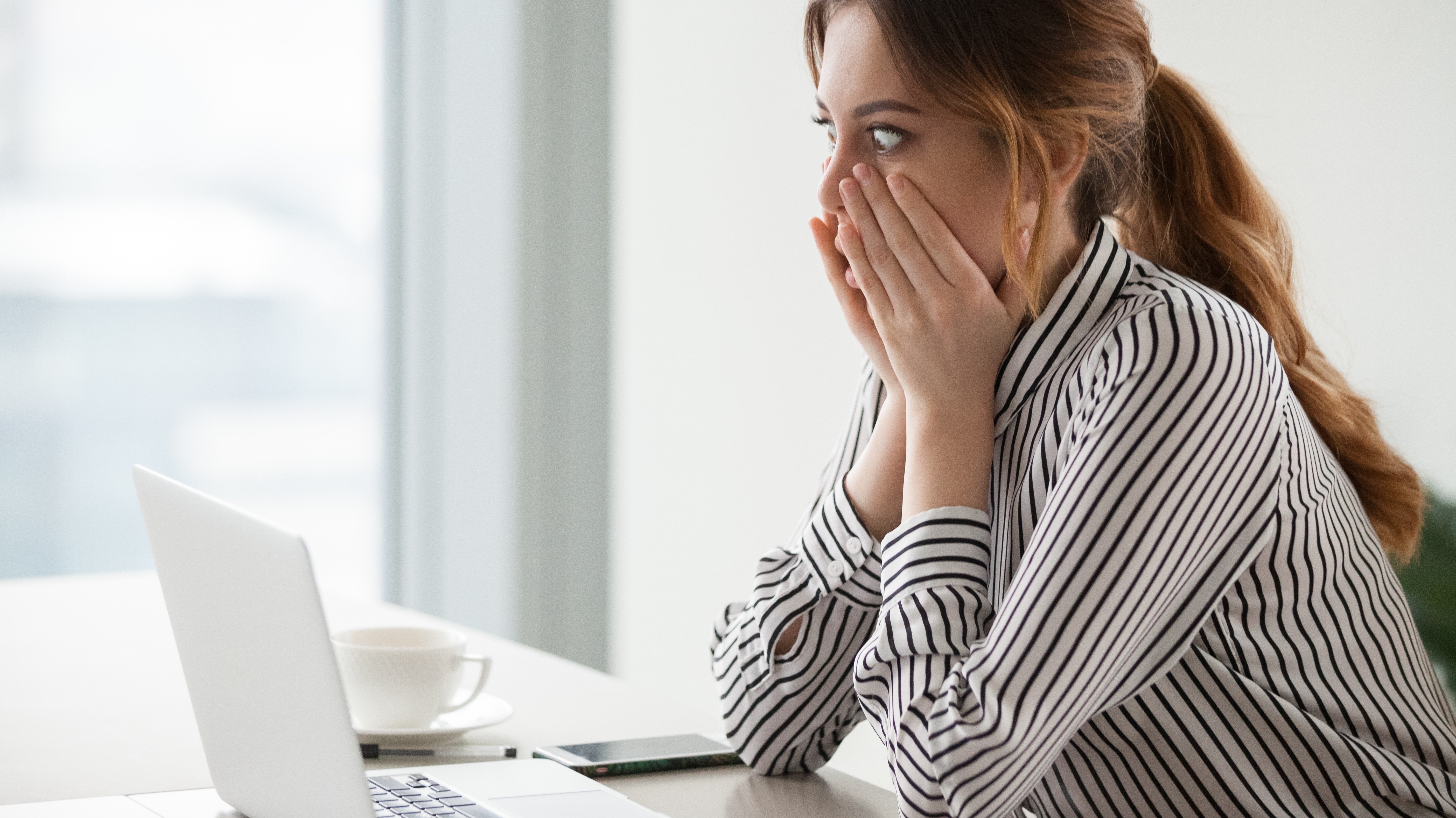 Shocked woman worker looking at Windows laptop screen
