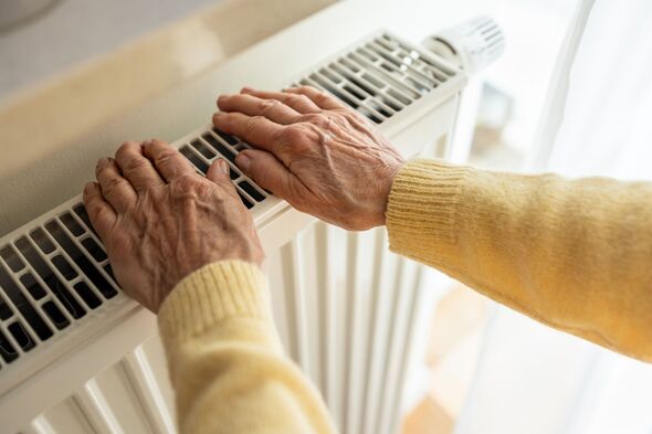 Senior woman warming her hands on a radiator at home, close-up Senior woman warming her hands on a radiator at home, close-up