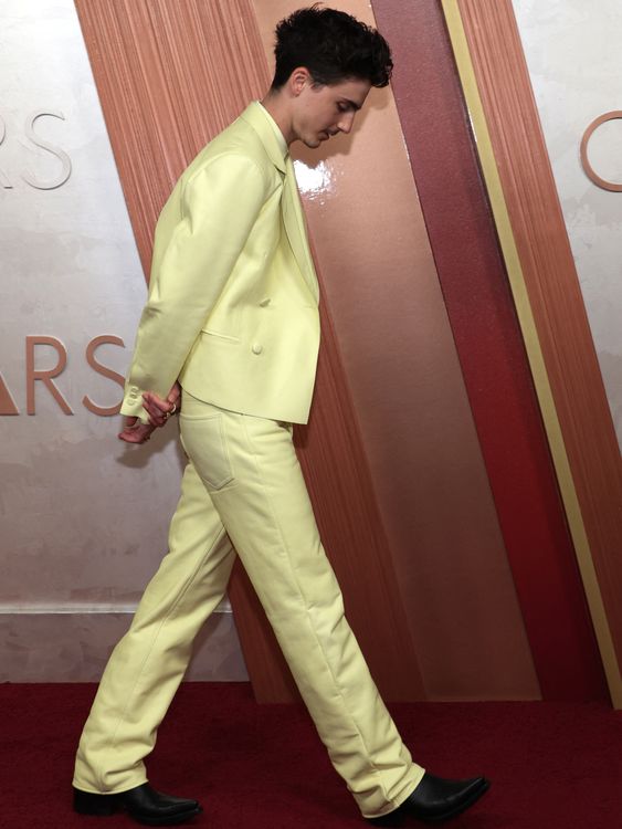 A bright 'butter yellow' Givenchy suit for Timothee Chalamet in 2025, with matching silk shirt, a Cartier diamond choker, and black boots. Pic: Reuters