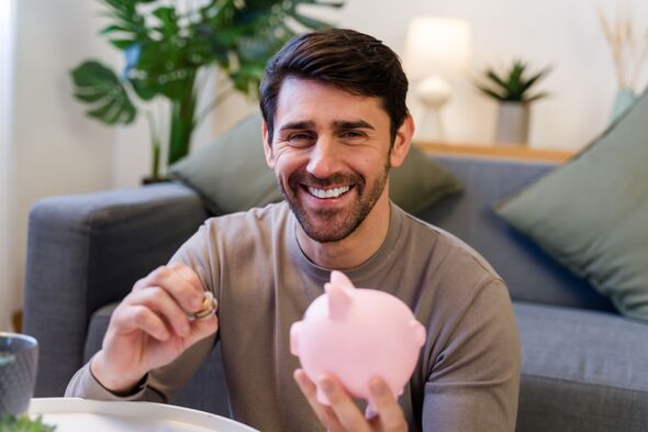Smiling man adding coins to a piggy bank