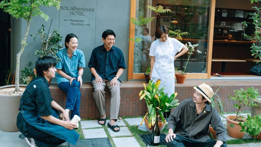 People sitting outside on a bench next to a building