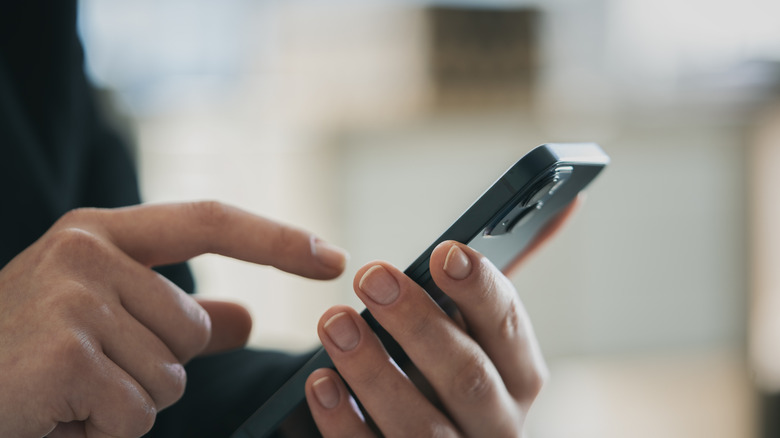 A person actively using a smartphone while holding it