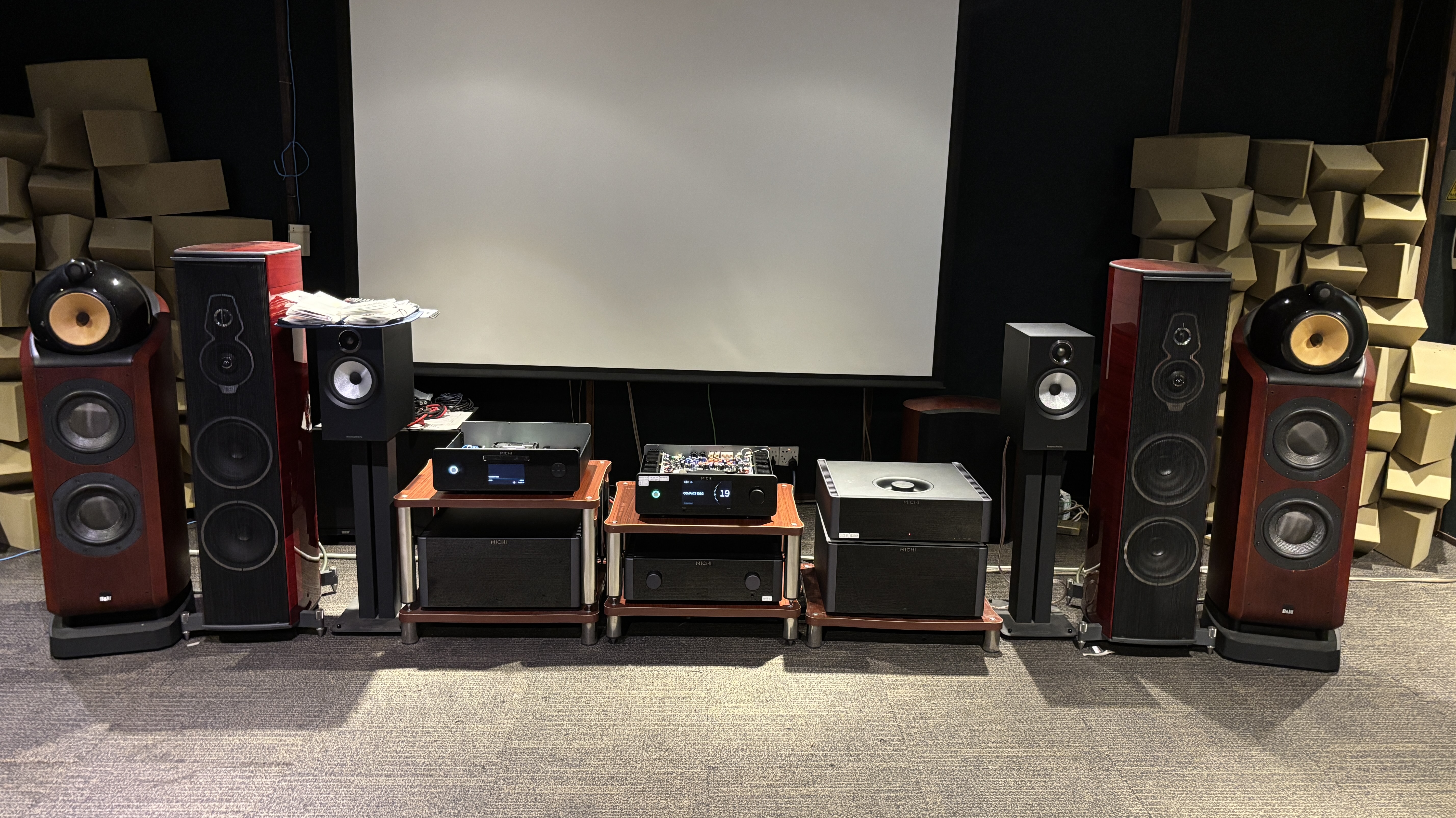 Rotel Michi Prestige range electronics on a hi-fi rack in a listening room next to various speakers