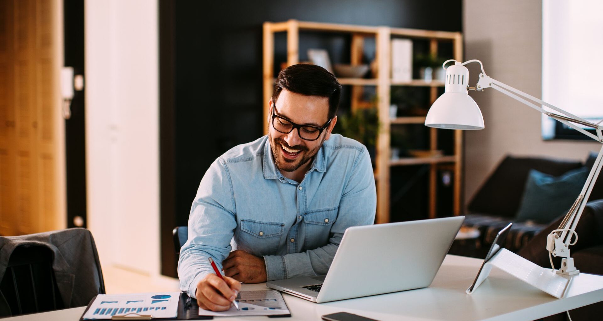 Young business man working at home with laptop and papers on desk