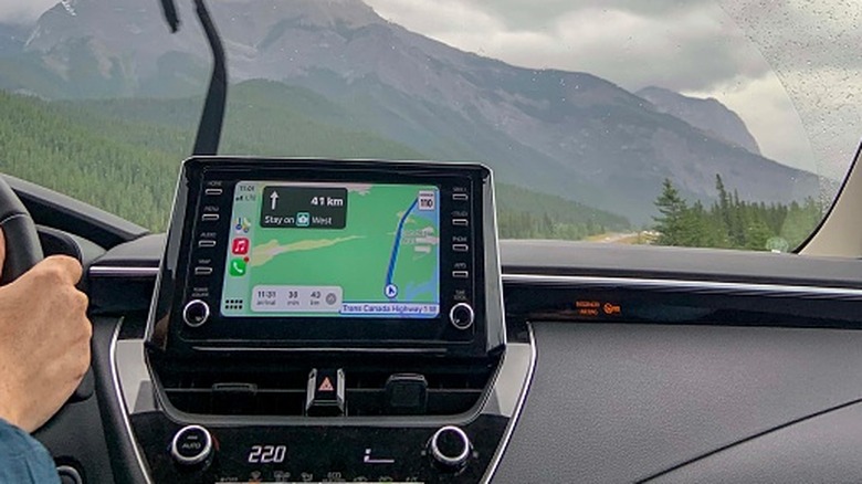 a person driving with Apple CarPlay navigation on the screen