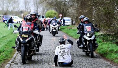 A protestor sits on the road while riders compete in the 'Ronde van Brugge' men's elite one-day cycling race, 202,9 km from and to Bruges on March 25, 2026. (Photo by MAARTEN STRAETEMANS / Belga / AFP) / Belgium OUT