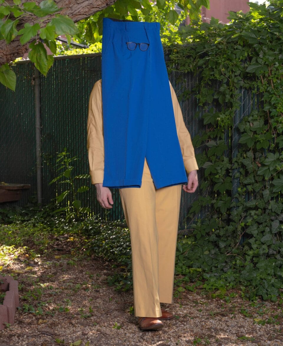 a surreal portrait by photographer Ben Zankn depicting a figure wearing a pair of bold blue pants on his face, with glasses over them