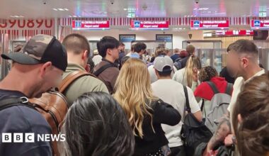 A crowd of passengers waiting in the passport control queue at Milan Bergamo airport on 16 April,  with four check-in desks visible.