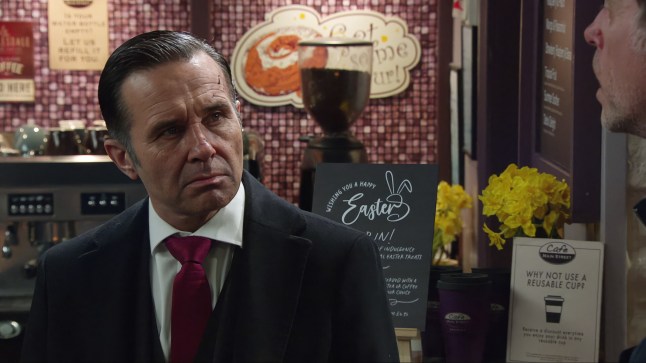 Graham Foster looking serious while standing in the cafe in Emmerdale.