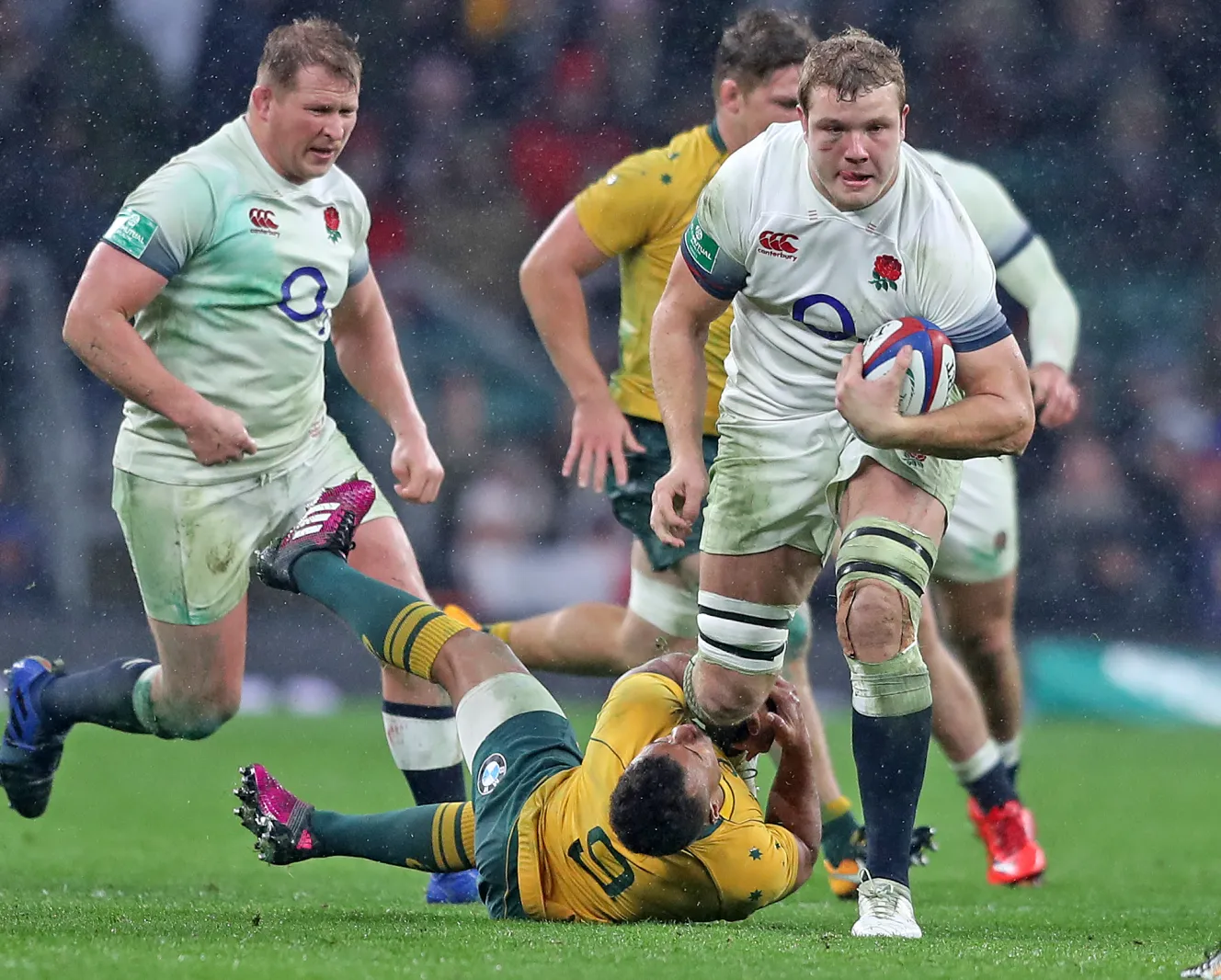 Joe Launchbury of England surges through a tackle by Will Genia of Australia.