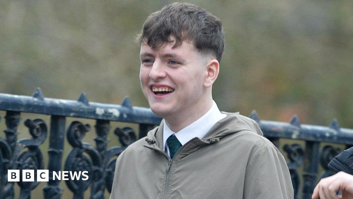 Ciaran Wason wearing a shirt, tie and grey/green jacket. He has short, brown hair and is smiling.