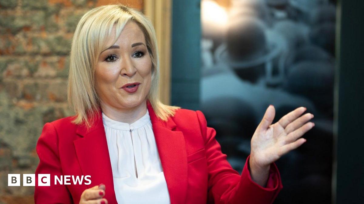 Two girls smiling at the camera as they pose for a picture in a youth club. Maisie on the left has brown hair pulled back in a pony tail and is wearing a grey hoodie with Harvard University branding in large red type. Iga on the right wears a black hoodie bunched up on her arms. She has shoulder-length blond hair and has rimless glasses.