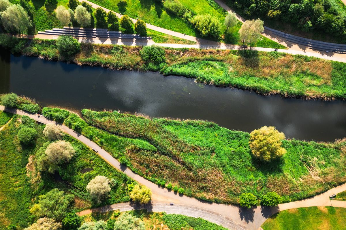 Aerial top down view, taken by drone, depicting the pathways and green lush foliage of the wetlands walk at Stratford in East London, alongside the River Lea.