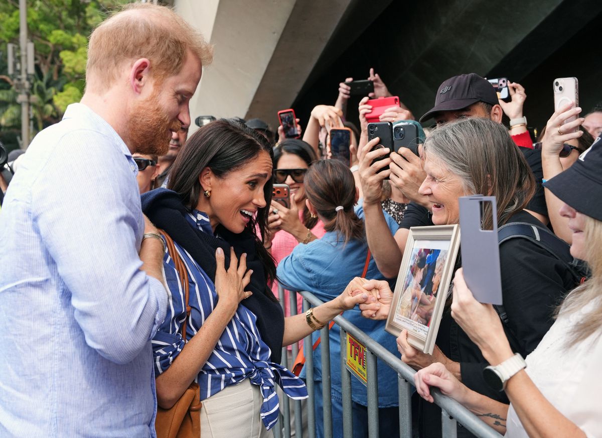 A wellwisher presents Prince Harry and Meghan