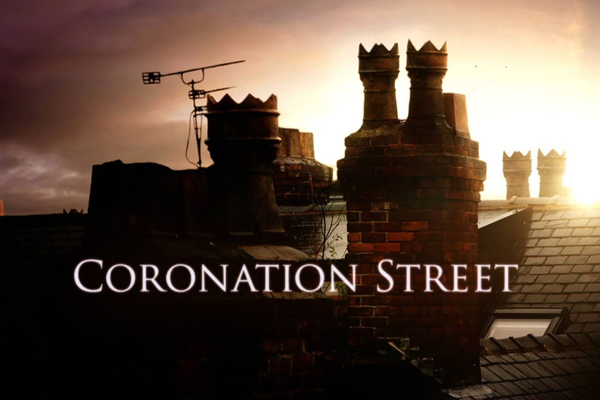 The iconic skyline of Coronation Street is captured at sunset, with a construction site visible in the background and a silhouette of a chimney prominently displayed.