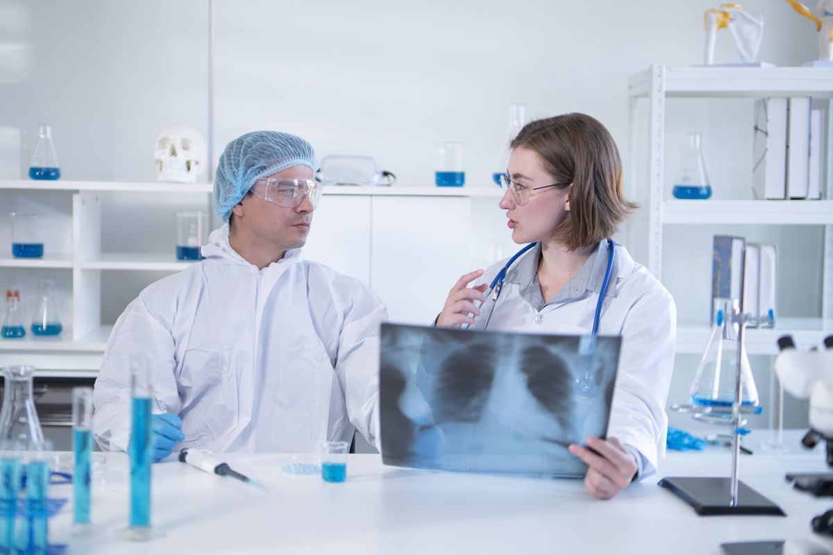 Female doctor and medical person considering lungs X-ray film at hospital