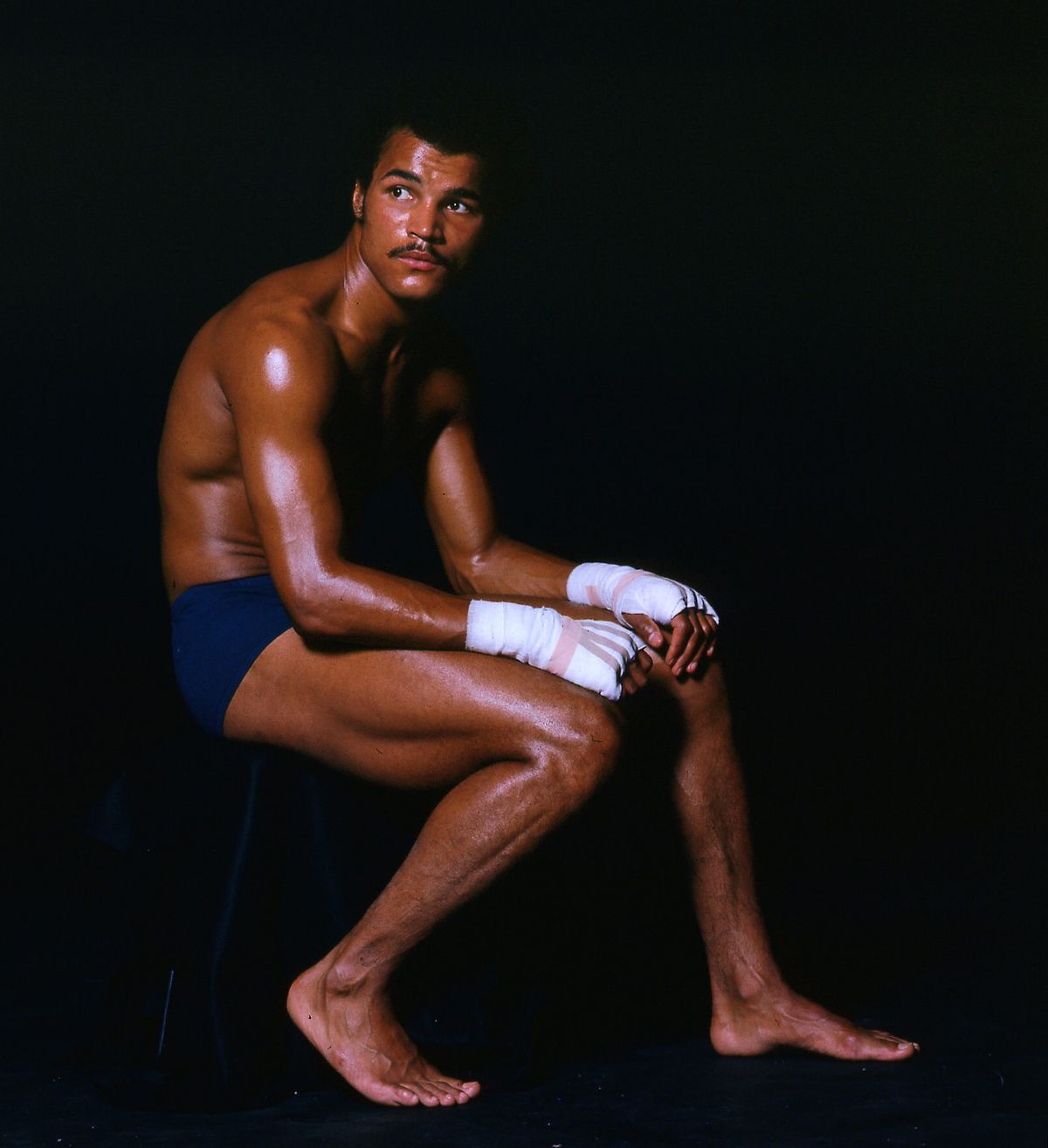 Boxer John Conteh as a young man sitting with his hands bandaged for a fight