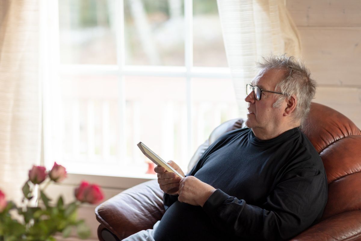 Senior man staring TV from the couch in cozy living room at home. Finland, Europe