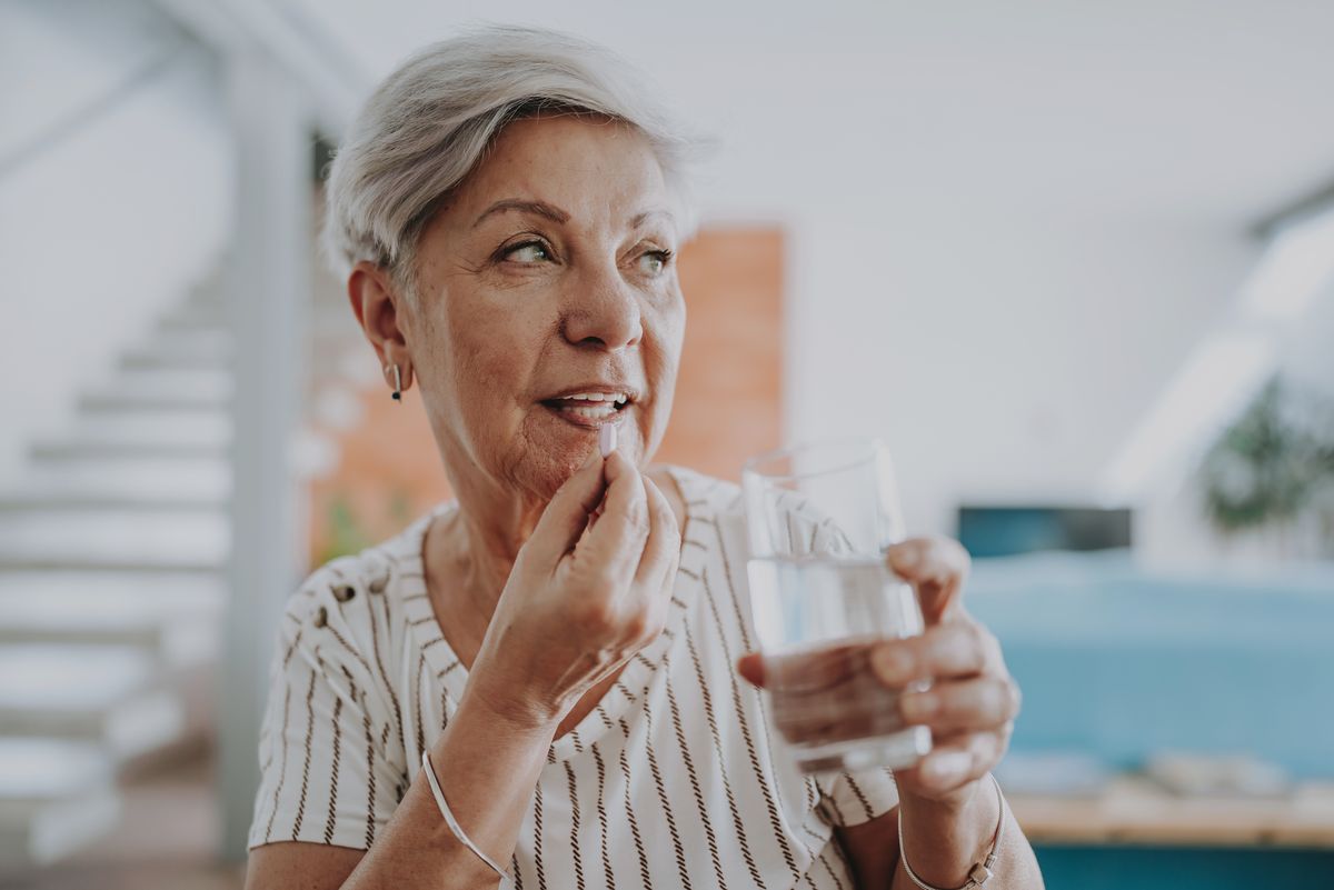 Senior woman taking medicine at home