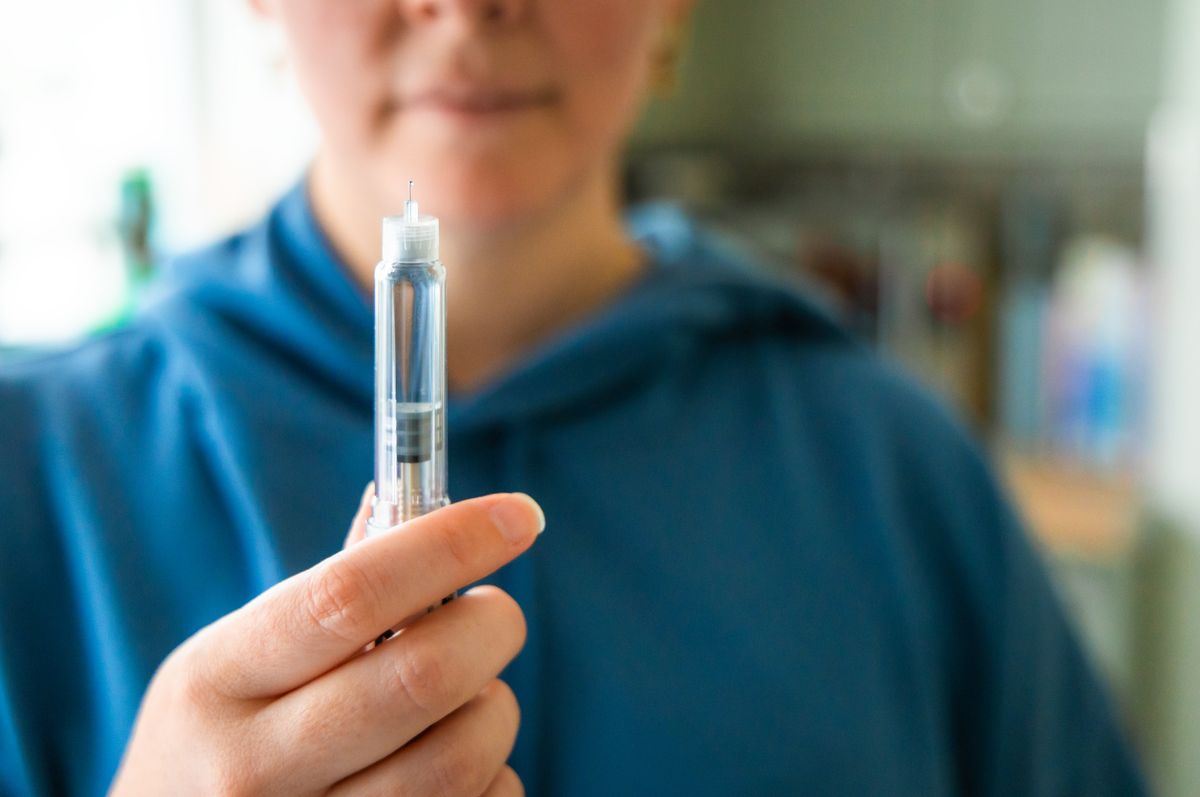 Close up of a woman's hands holding an injection pen
