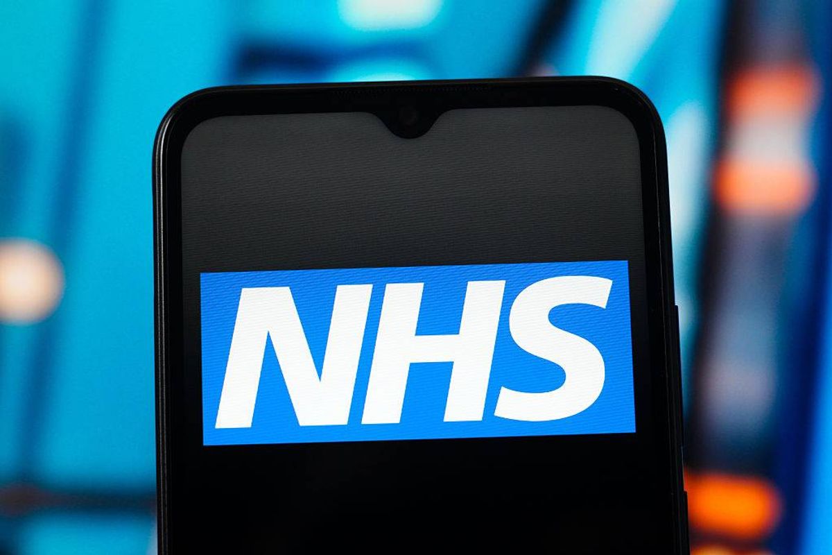 An image displays the logo for NHS, displayed prominently on the screen of a smartphone against a blurred, multicolored background, signifying digital presence and accessibility.