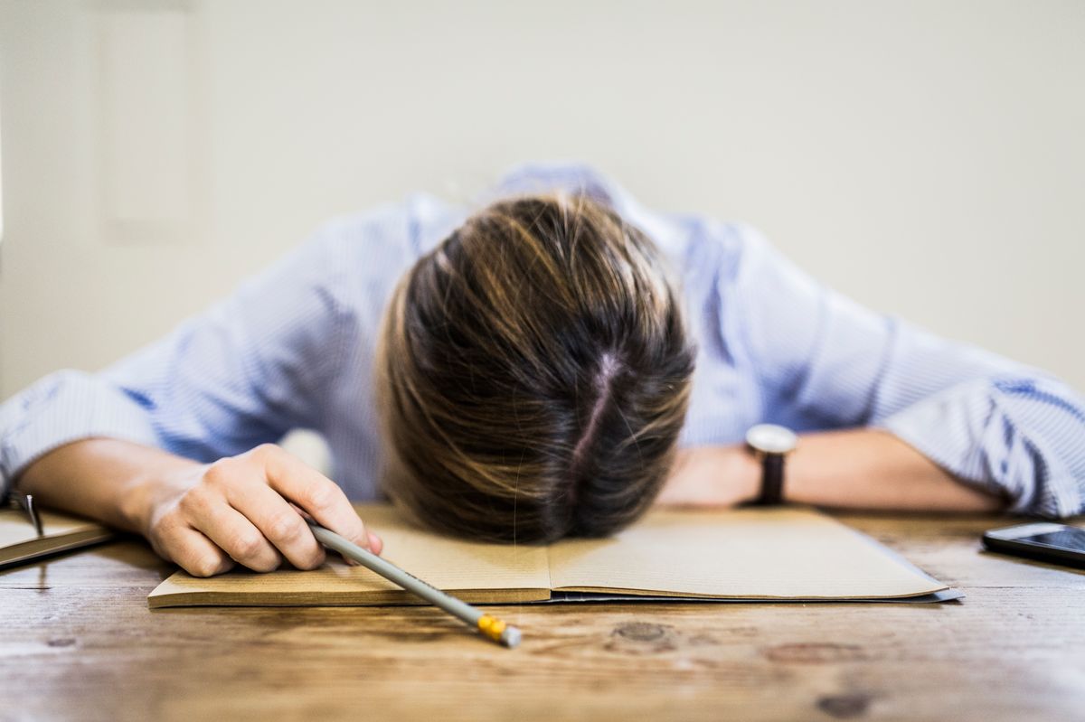 Close-up of woman lying on notebook at desk - stock photo