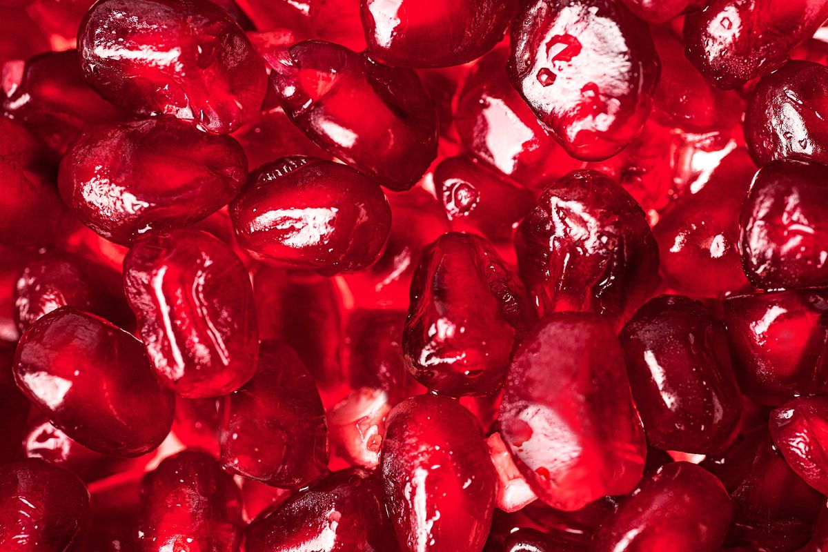 Pomegranate seeds background. Сomposition of pomegranate seeds in  Color of the Year 2023 Viva Magenta. Close up. Copy space.