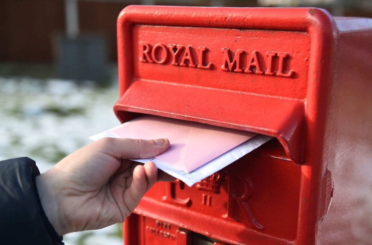 Hand putting mail into red post box