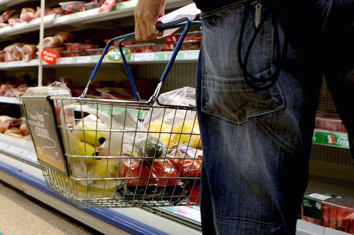 Person holds a shopping basket in a supermarket