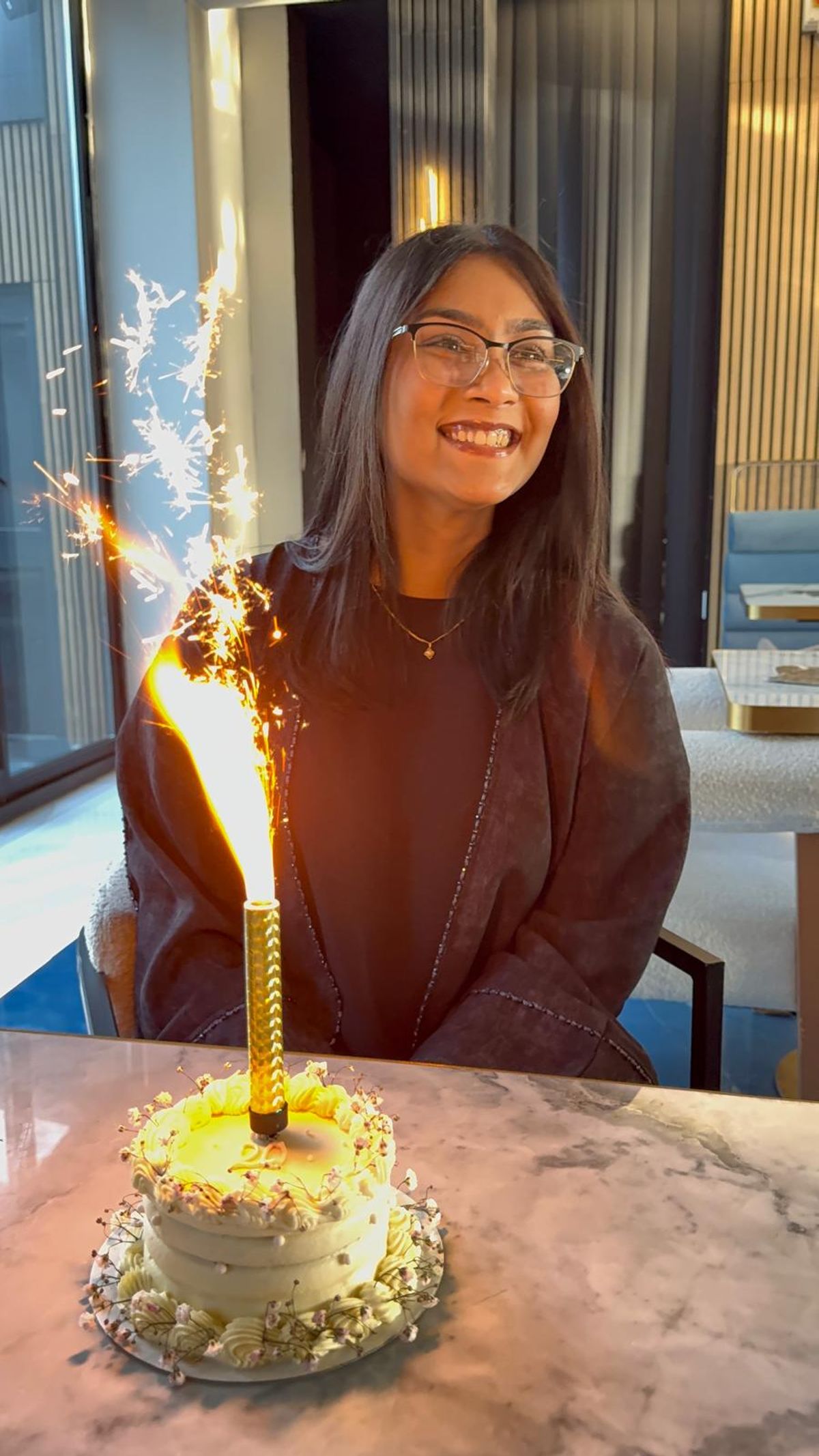 Tash on her 20th birthday in front of a cake with a huge sparkler