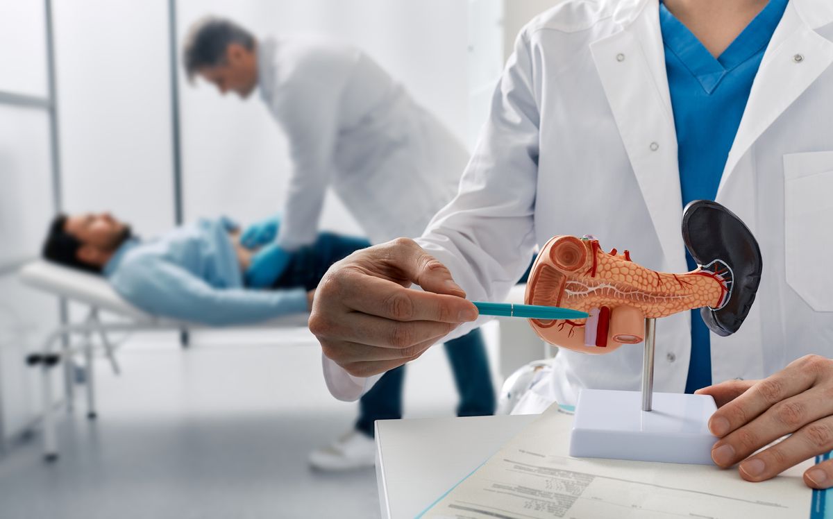 A doctor examines a male patient's belly in a clinic to determine the condition of his pancreas